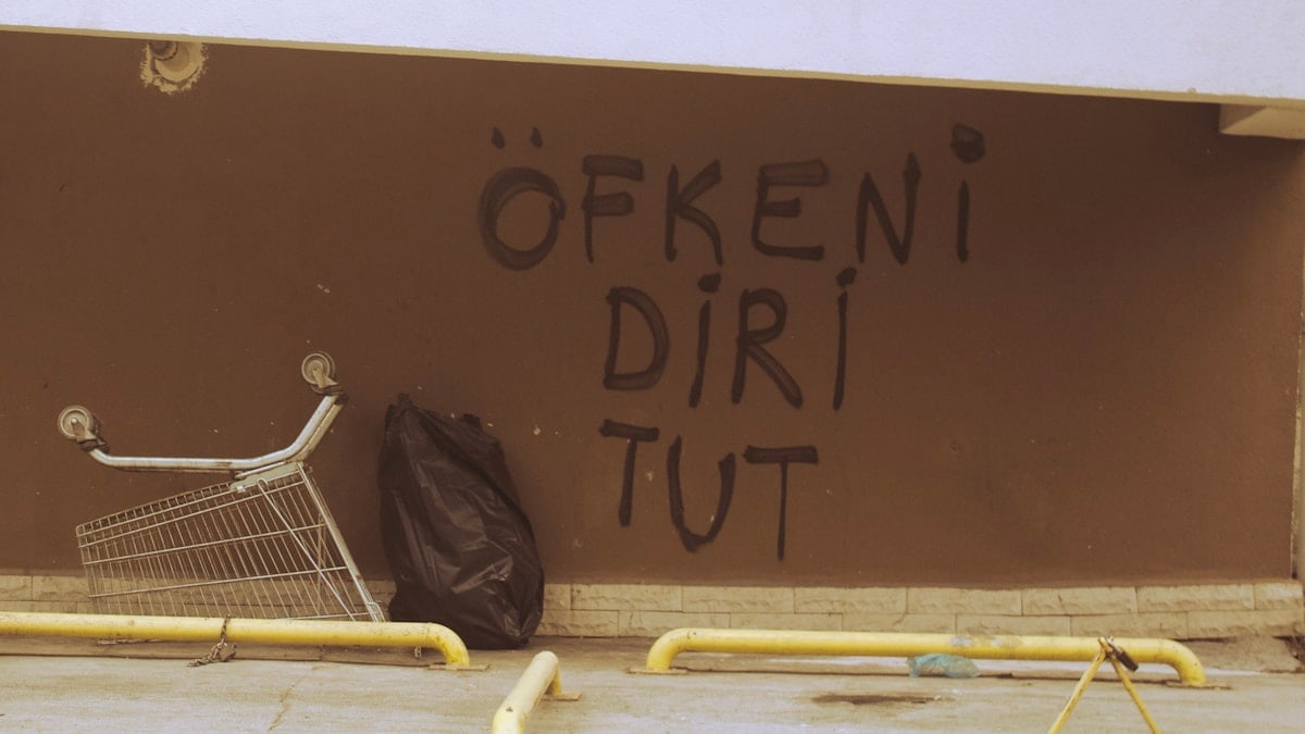 a shopping cart leaning against a wall with graffiti on it